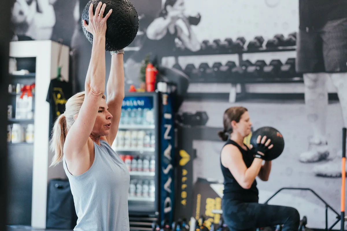 Members over 40 training with medicine balls in a coached small group session at Alloy Personal Training