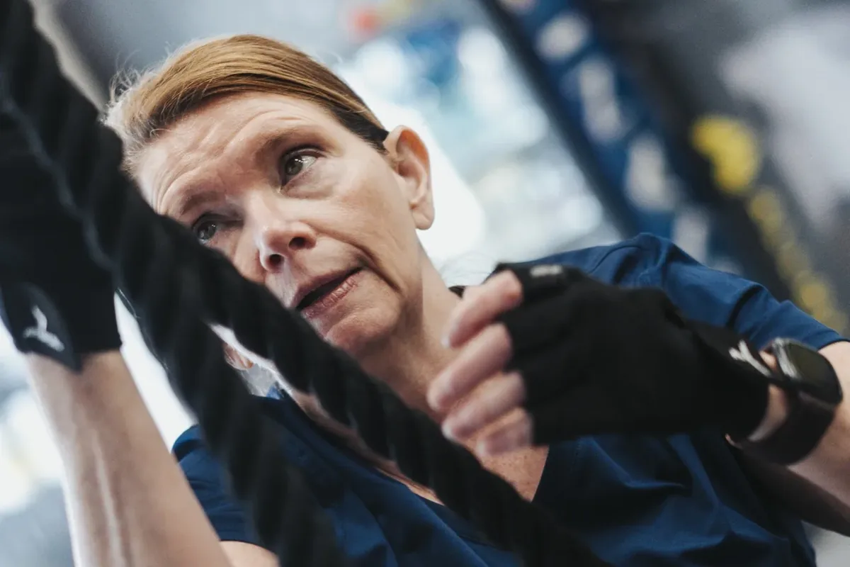A close-up of a woman gripping battle ropes mid-workout at an Alloy Personal Training studio