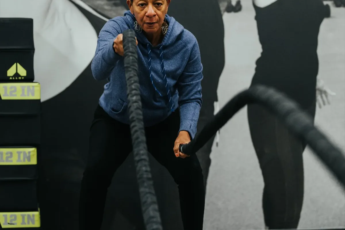 An older member works through a battle-rope interval during a strength session at an Alloy Personal Training studio